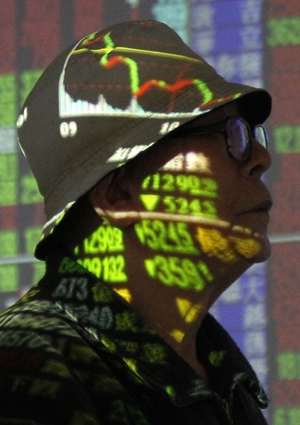 © Reuters. Stock market prices are cast on a man inside a brokerage in Taipei