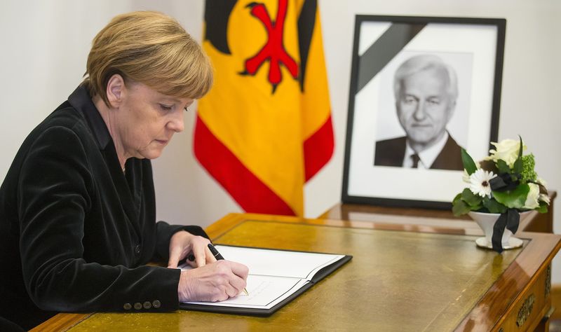 © Reuters. German Chancellor Angela Merkel writes in the condolence book for the former German President von Weizsaecker in Berlin