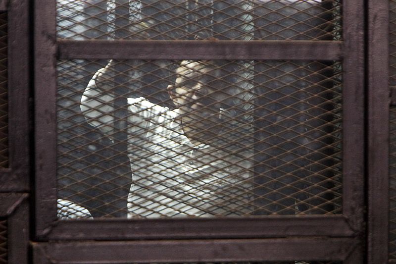 © Reuters. Muslim Brotherhood supporter convicted of playing a role in the killings of 16 policemen in August 2013 stands behind bars during their trial in Cairo