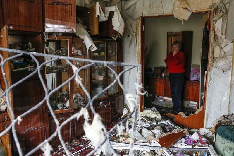 © Reuters. A woman reacts as she looks at the debris inside a flat at a residential block damaged by a recent shelling in Yenakieve