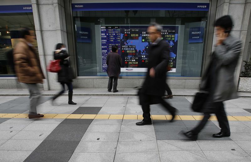 © Reuters. A man looks at an electronic board showing the stock market indices of various countries outside a brokerage in Tokyo