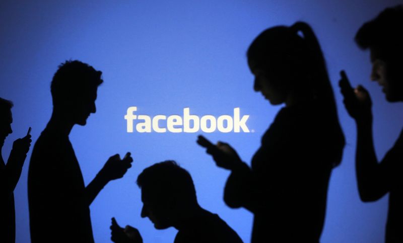 © Reuters. People pose with mobile devices in front of projection of Facebook logo in this picture illustration taken in Zenica