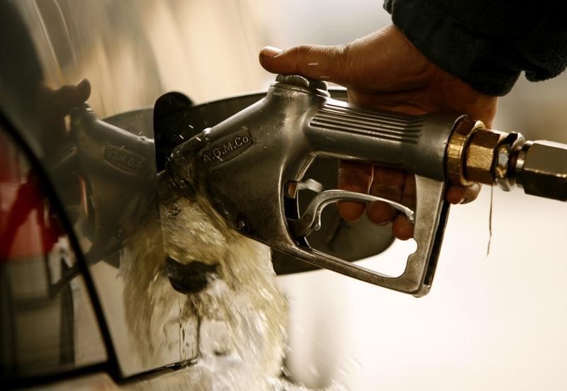 © Reuters. Fuel overflows as an Iranian man pumps gasoline into his car at a gas station in Tehran