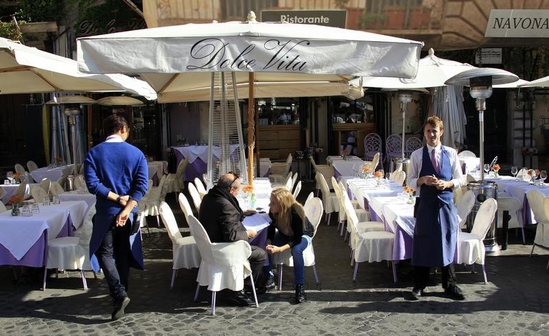 © Reuters. A waiter waits for customers at a bar in downtown Rome