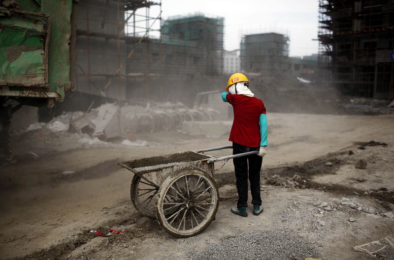 © Reuters. File photo of a migrant construction worker, shielding her face from dust during a shift at a residential construction site in Shanghai