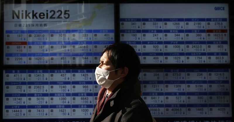 © Reuters. Man walks past a stock quotation board outside a brokerage in Tokyo