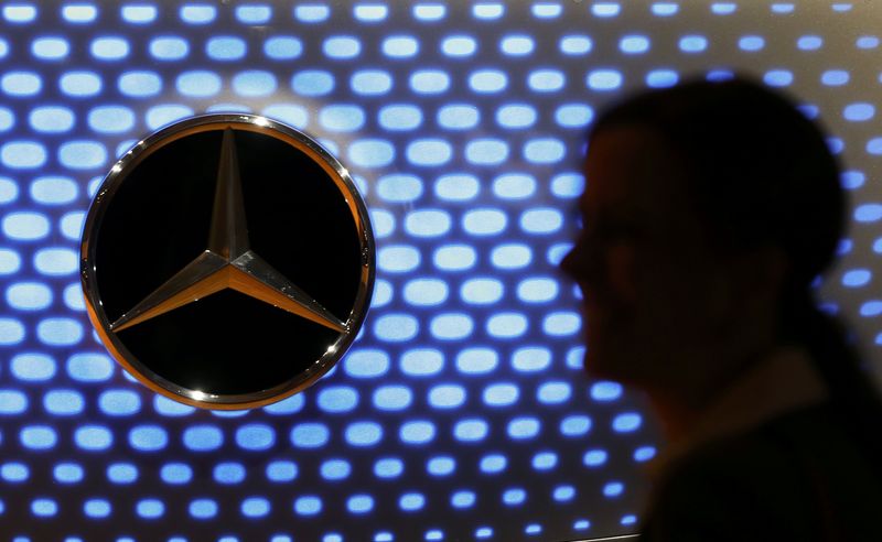 © Reuters. A journalist is silhouetted against a car bonnet emblem of a Mercedes-Benz car at the annual news conference of Daimler AG in Stuttgart
