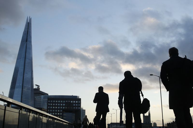 © Reuters. Workers pass the Shard as they cross London Bridge in the City of London