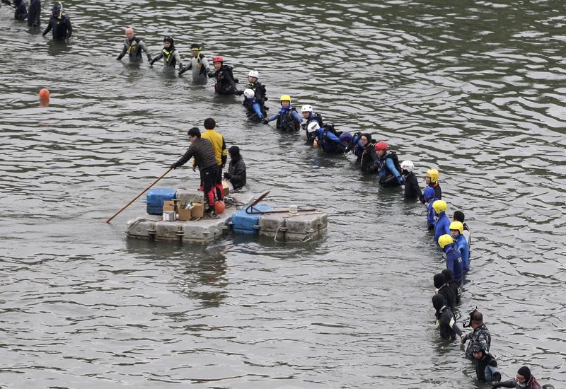 © Reuters. Equipes de emergência realizam buscas em local de queda de avião da TransAsia Airways em rio de Taipé