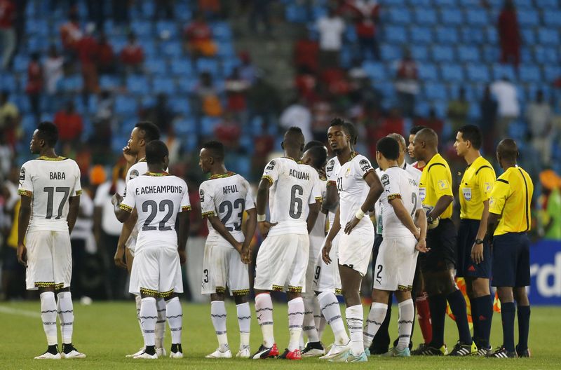 © Reuters. Referee Otogo-Castane stands next to Ghana players after Equatorial Guinea fans threw objects during their African Nations Cup semi-final soccer match in Malabo