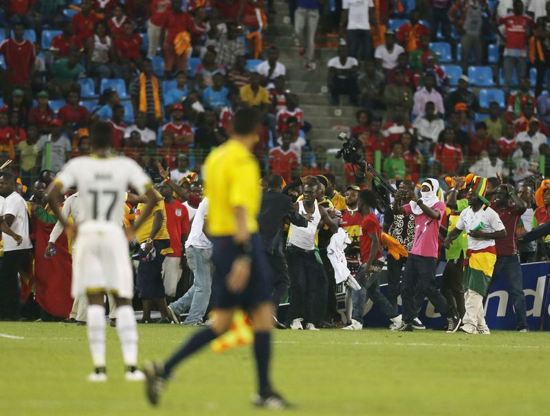 © Reuters. Security and CAF officials try to protect Ghana fans after Equatorial Guinea fans threw objects during their African Nations Cup semi-final soccer match in Malabo