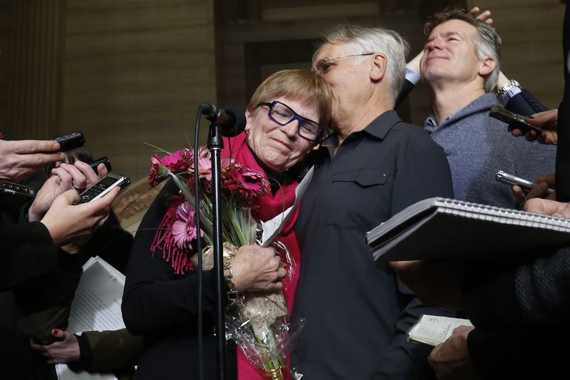 © Reuters. Carter  embraces her husband Johnson while speaking to journalists at the Supreme Court of Canada in Ottawa