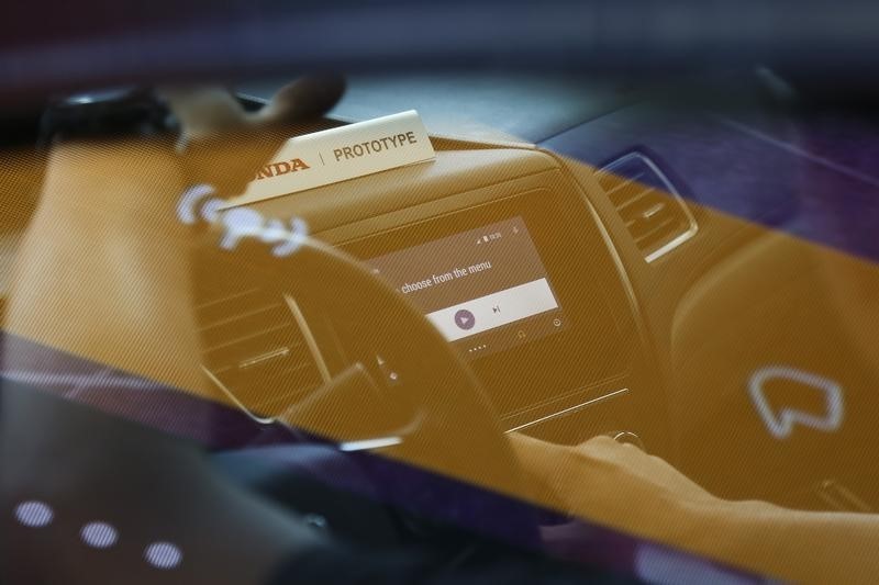 © Reuters. A reflection of a Google employee demonstrating the Android Auto interface for a conference attendee, is seen on a large screen outside the car at the Google I/O developers conference in San Francisco