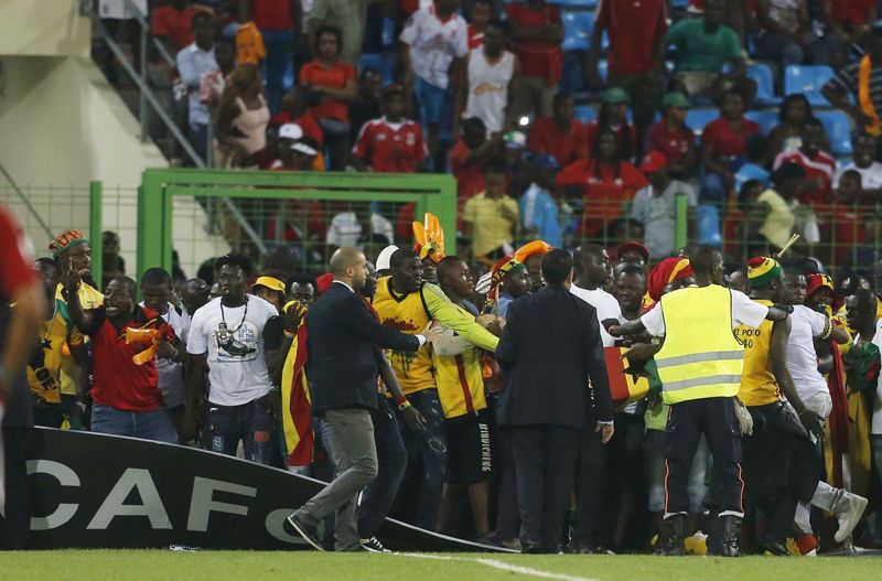 © Reuters. Security and CAF officials try to protect Ghana fans after Equatorial Guinea fans threw objects during their African Nations Cup semi-final soccer match in Malabo