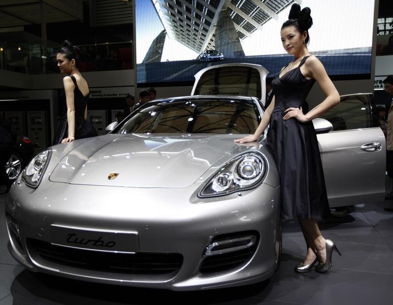 © Reuters. Models stand next to a Porsche's Panamera S at the Shanghai International Auto show