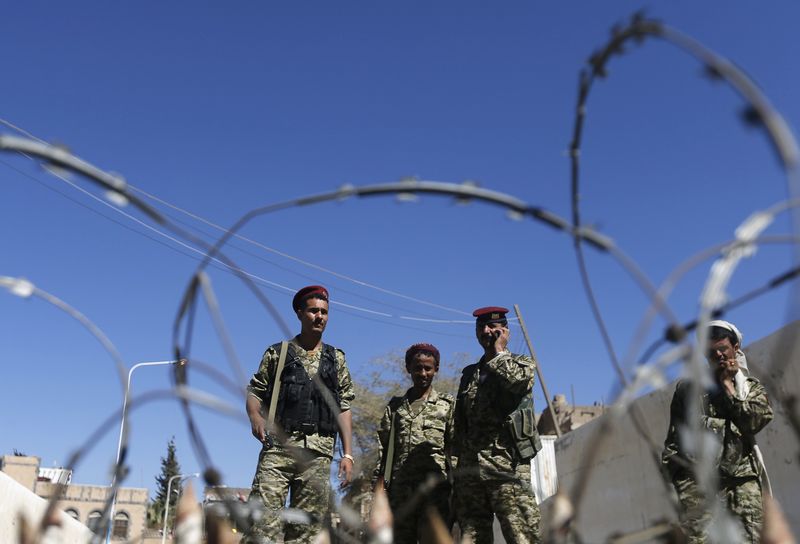 © Reuters. Houthi militiamen and soldiers stand behind a roadblock at the scene of a blast near the republican palace in Sanaa