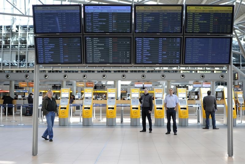 © Reuters. Passengers look at information displays at the Airport Fuhlsbuettel in Hamburg