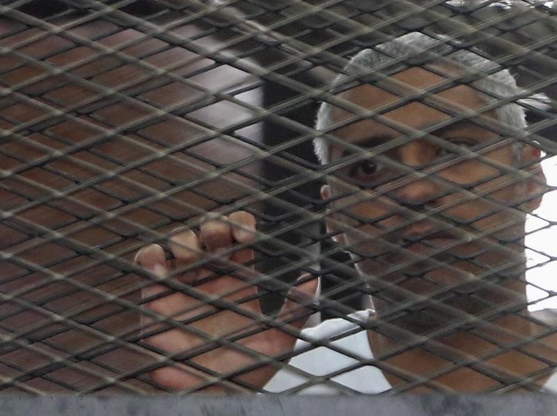 © Reuters. Al Jazeera journalist Mohammed Fahmy stands behind bars at a court in Cairo