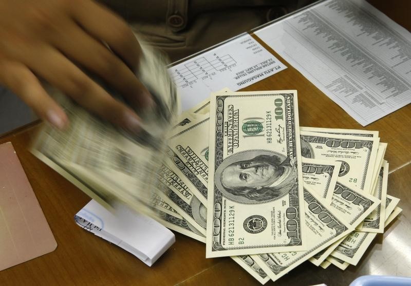 © Reuters. A money changer holds stacks of US dollar notes in Jakarta