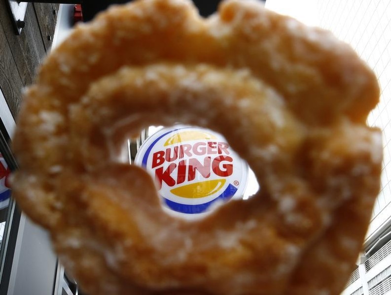 © Reuters. The Burger King logo is seen through a Tim Horton's doughnut hole in a photo illustration outside a restaurant in Toronto