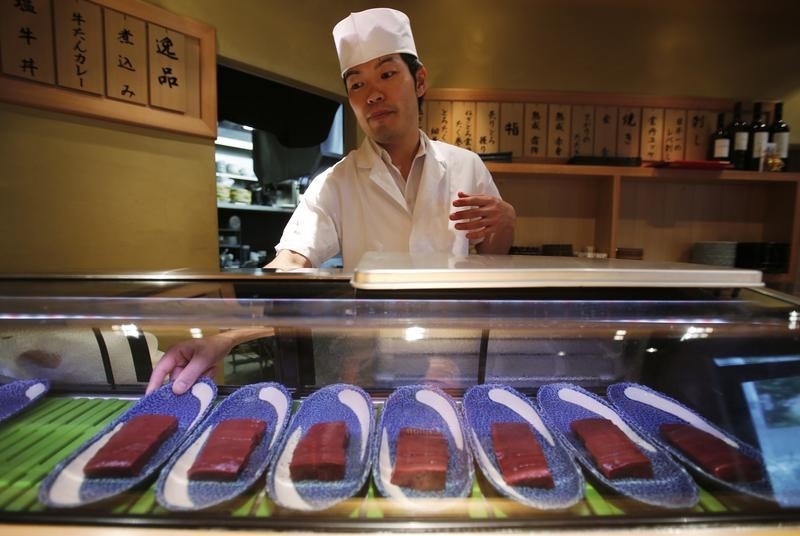 © Reuters. A chef places raw beef liver sashimi in a refrigerated case at a restaurant in Tokyo