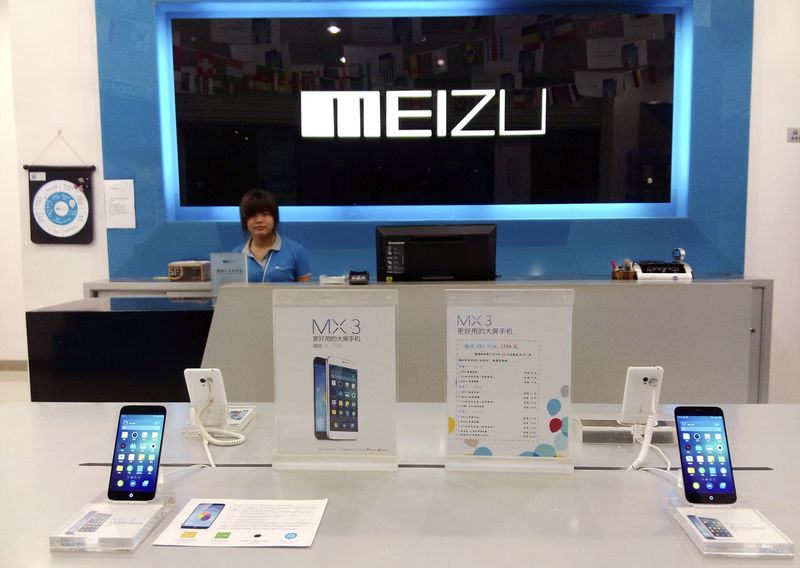 © Reuters. Shop assistant waits for customers at a Meizu store as Meizu MX3 smartphones are seen on display in the foreground, in Shenzhen