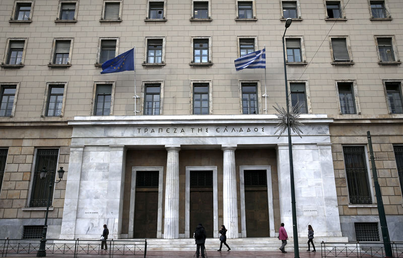 © Reuters. An European Union flag and a Greek national flag flutter as people make their way past the headquarters of Bank of Greece in Athens