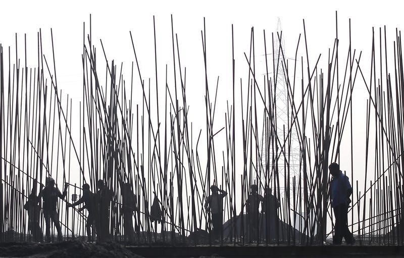 © Reuters. Labourers work at the construction site of a bridge being built over the river Yamuna for metro rail in New Delhi