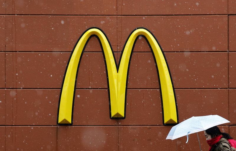 © Reuters. A woman walks past the logo of McDonald's outside its restaurant in Tokyo