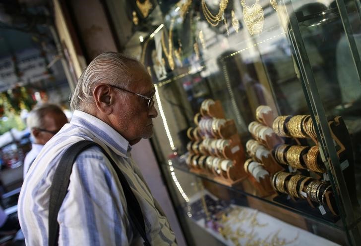 © Reuters. Мужчина рассматривает золотые браслеты на витрине ювелирного магазина в Мумбаи
