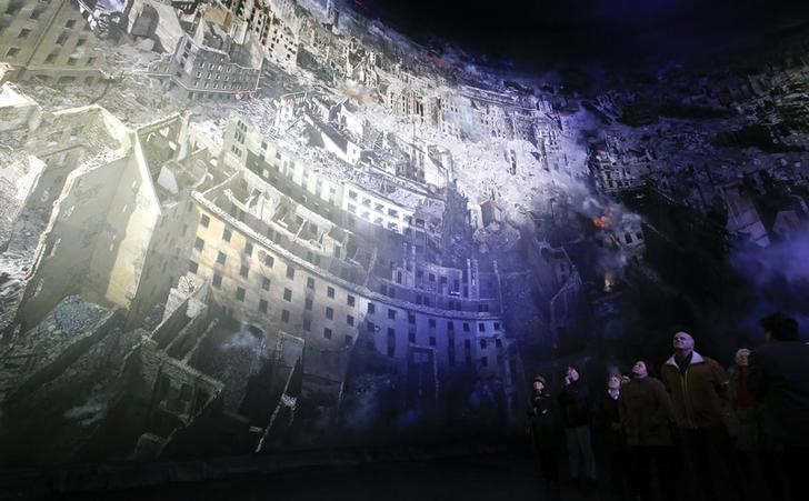 © Reuters. Visitors watch the 'Dresden 1945' 360 degrees panorama showing the destroyed city of Dresden after the bombing raids during the World War Two in February 1945 at the Panometer in Dresden