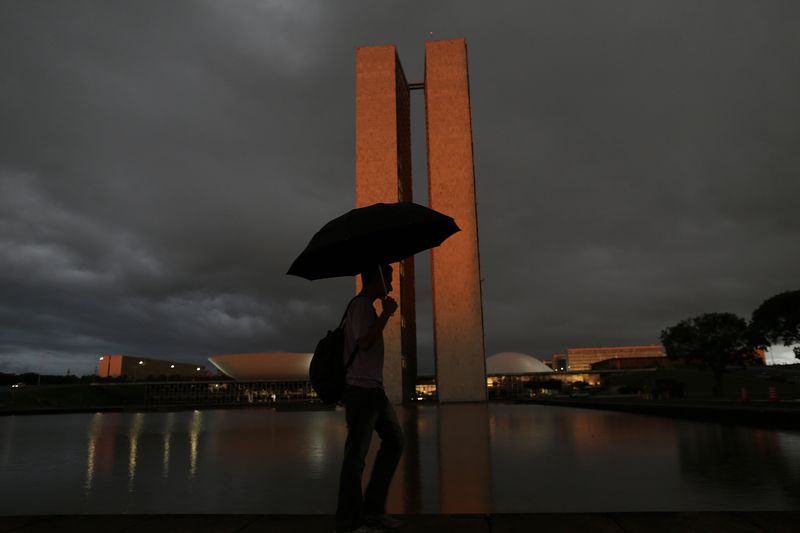 © Reuters. Homem com guarda-chuva passa em frente ao prédio do Congresso Nacional, em Brasília