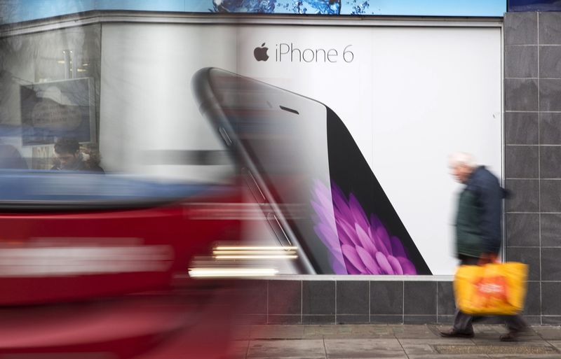 © Reuters. A bus and pedestrian pass an advertisement for the Apple iPhone 6 in north London