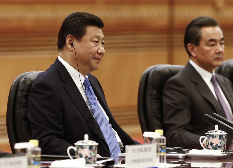 © Reuters. Chinese President Xi listens with an earpiece as Chinese Foreign Minister Wang looks on during a meeting with Argentinian President Kirchner at the Great Hall of the People in Beijing