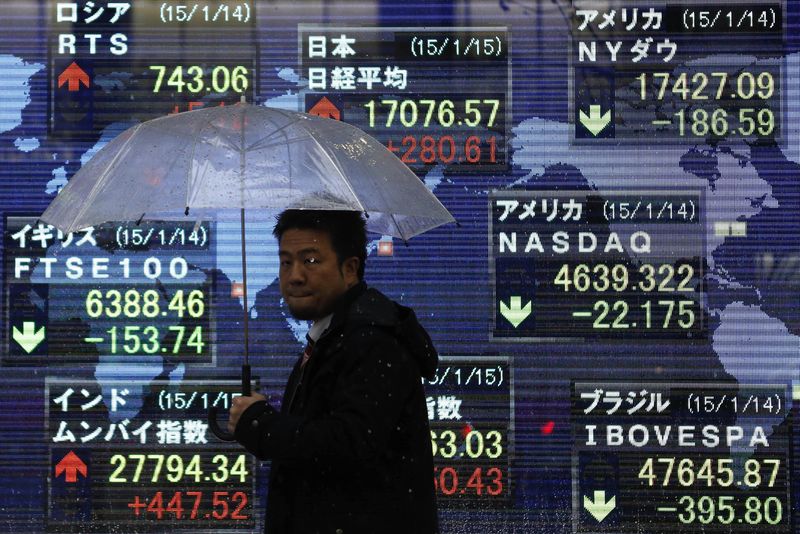 © Reuters. A pedestrian walks past an electronic board outside a brokerage in Tokyo