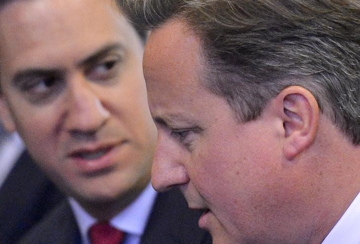 © Reuters. Britain's Prime Minister Cameron speaks to the leader of the opposition Labour Party Miliband as they wait to listen to Canadian Prime Minister Stephen Harper address members of the Houses of Parliament in the Palace of Westminster, in central London