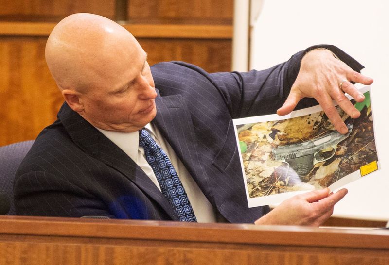 © Reuters. Massachusetts State Trooper Stephen Gallagher holds a picture of a small handgun found in a wooded area near the crime scene during the murder trial of Hernandez in Fall River