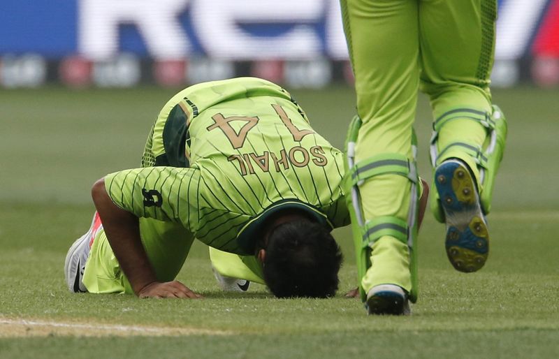 © Reuters. Pakistan bowler Khan kneels to the ground celebrating the dismissal of India's batsman Rahane during their Cricket World Cup match in Adelaide