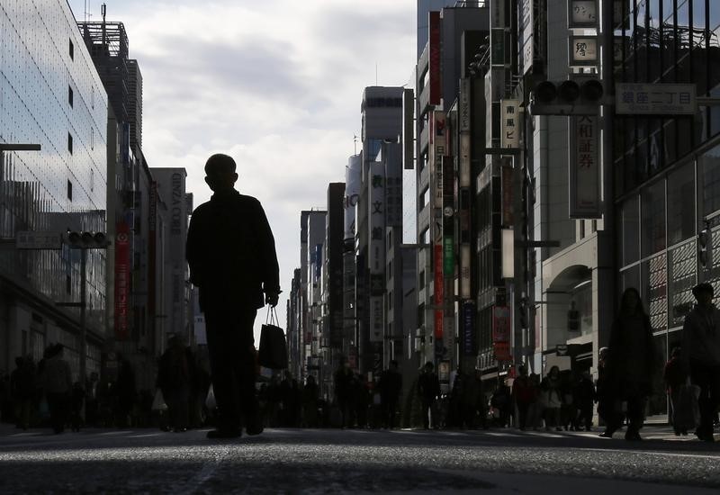 © Reuters. A man holding a shopping bag walks on a street at Tokyo's Ginza shopping district