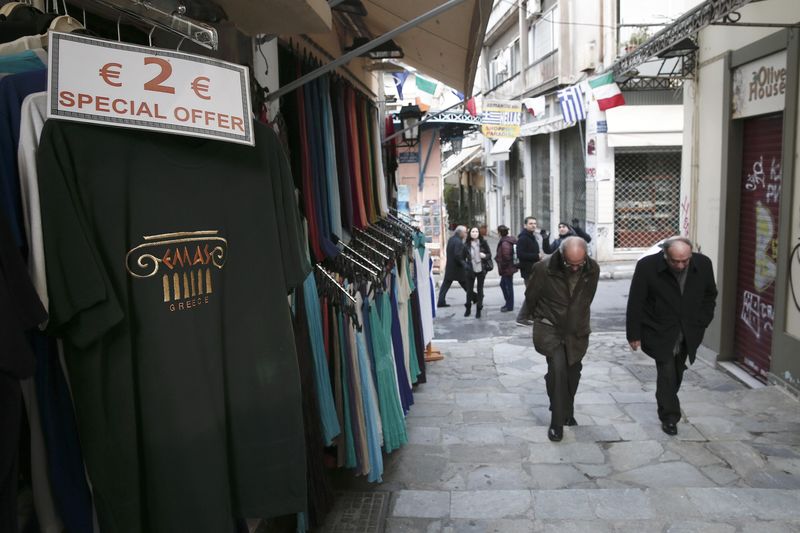 © Reuters. People walk by a souvenir shop selling T-shirts on special offer at Plaka district in Athens