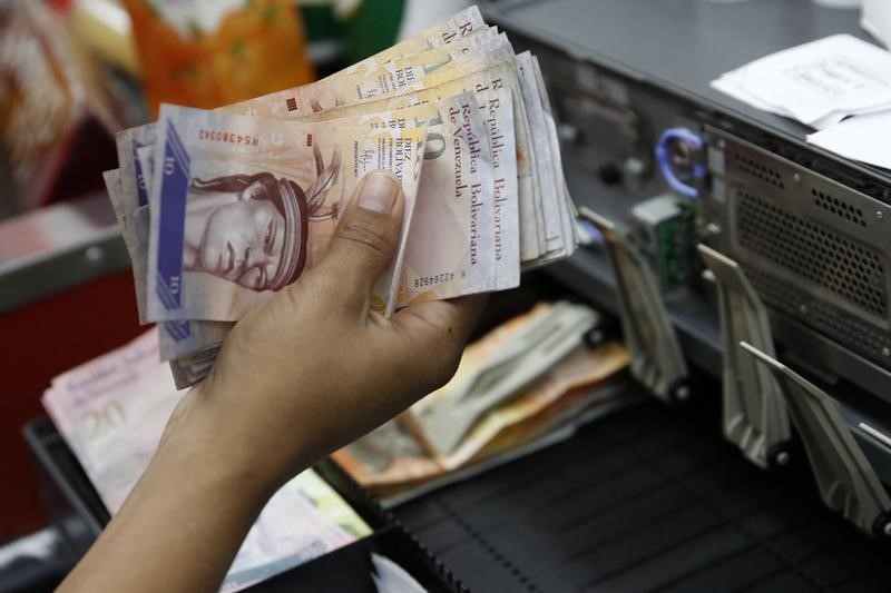 © Reuters. A cashier counts Venezuelan bolivar notes in a state-run supermarket in Caracas