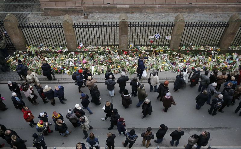 © Reuters. People pause for a moment of silence at a memorial site for the victims of the deadly attacks in front of the synagogue in Krystalgade in Copenhagen