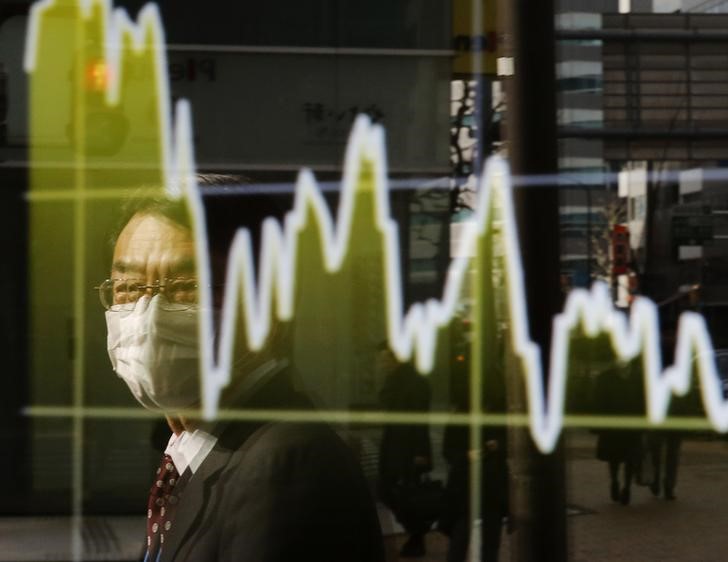 © Reuters. A man is reflected on an electronic board showing Japan's Nikkei average, outside a brokerage in Tokyo