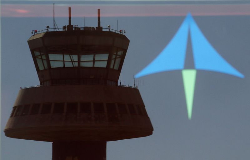 © Reuters. A control tower is reflected on a glass door next to an AENA logo at Barcelona's airport