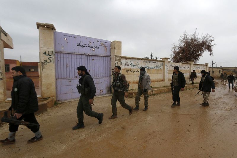 © Reuters. Rebel fighters carry their weapons as they walk into Ratian village, north of Aleppo