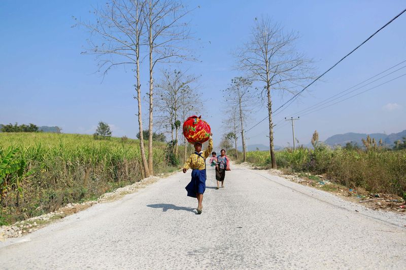 © Reuters. A family displaced by recent violence, walks down a road, in Laukkai