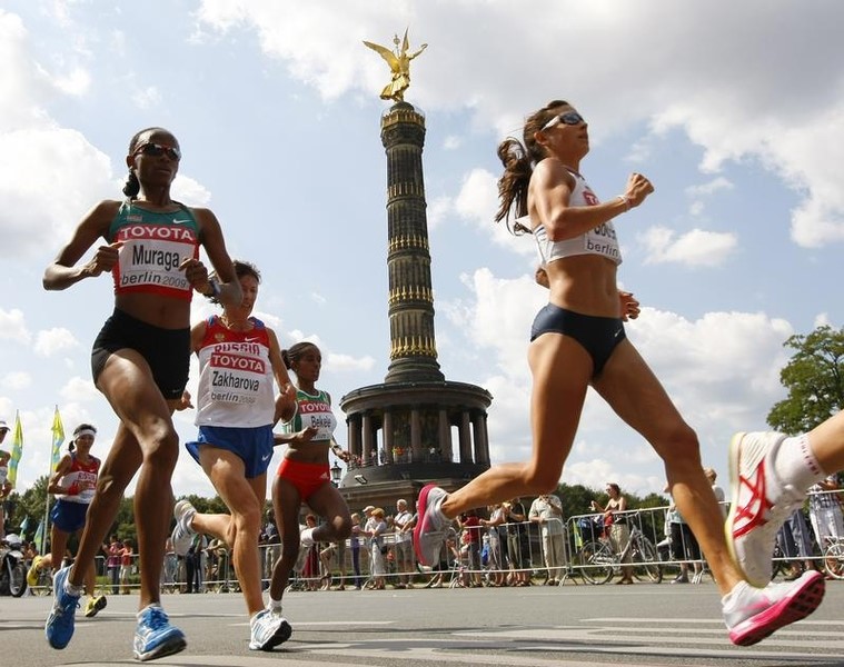 © Reuters. Muraga of Kenya runs ahead of Yulamanova of Russia and Bekele of Ethopia past the Victory Column during women's marathon at the world athletics championships in central Berlin
