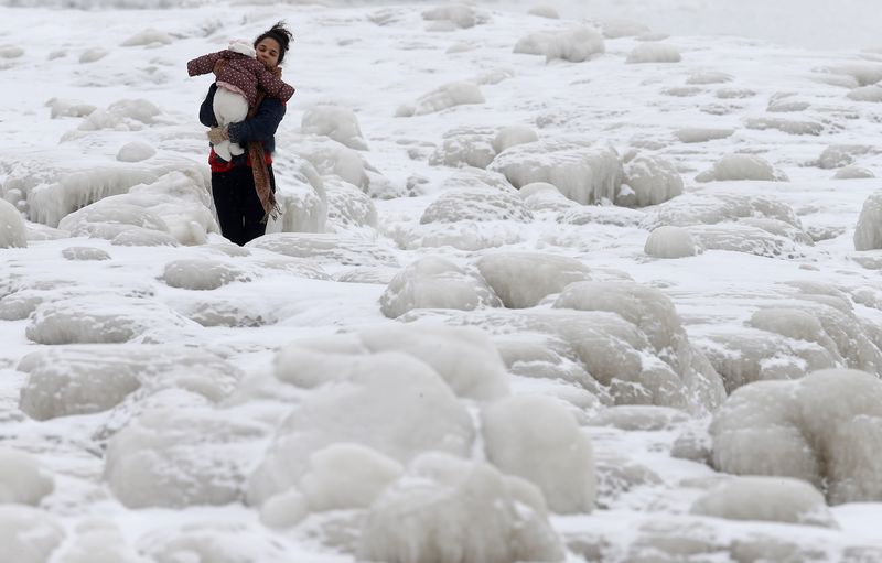 © Reuters. Mulher carrega bebê em meio ao gelo em Chicago