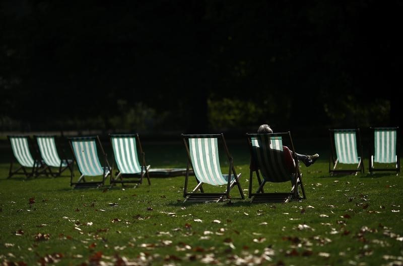 © Reuters. A visitor enjoys the autumn sunshine on a deck chair in St James Park, central London