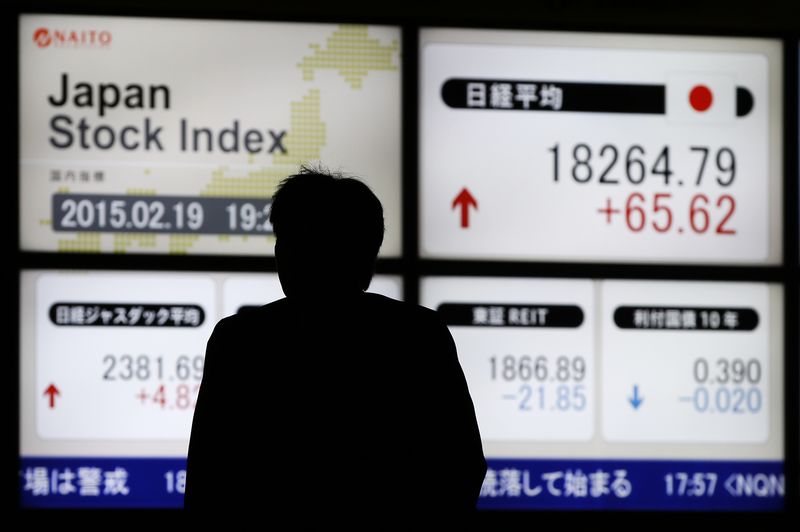 © Reuters. Man walks past an electronic board showing Japan's Nikkei average outside a brokerage in Tokyo